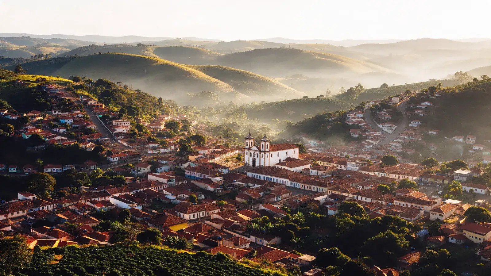 Vista aérea de uma cidade pequena do Sul de Minas entre morros